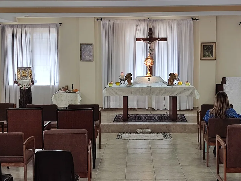 Altar, crucifijo y bancos de la capilla de la casa