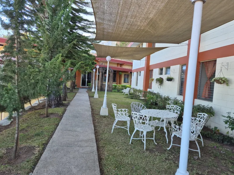 Corredor cubierto y mesas junto al jardín de la casa